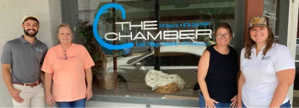 four people standing in front of a window that says the chamber