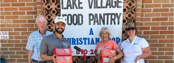four people standing in front of a sign that says lake village food pantry