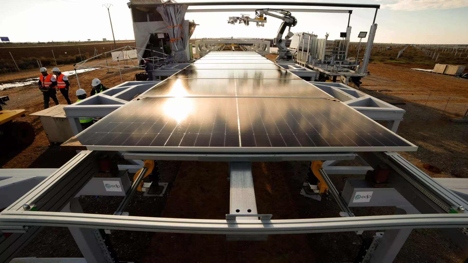 solar panel installation site using robotics, featuring mounted panels and a robotic arm assisting with positioning, while workers in safety gear oversee the process