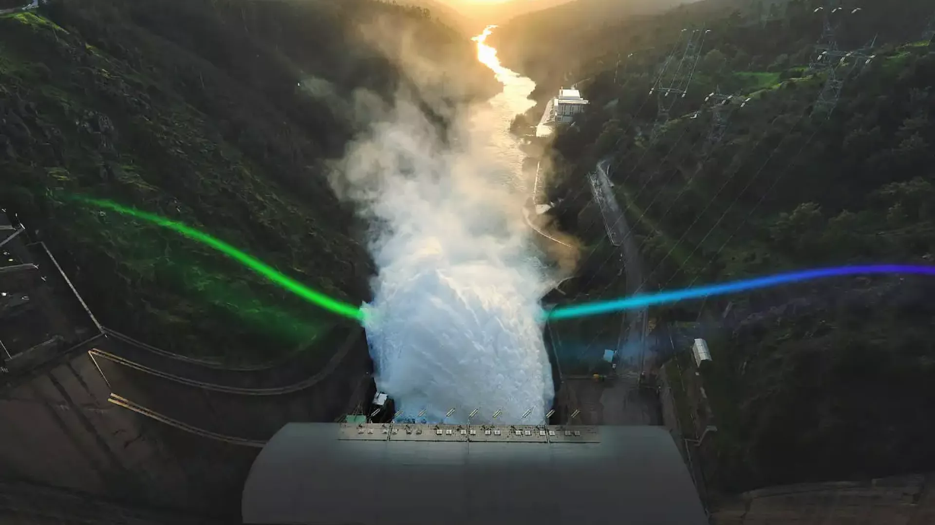 image of a dam in operation with a beam of light in the edp colors, a gradient from green to blue crossing the torrent of water that passes through the dam