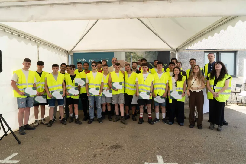 Group of young people with yellow reflective vests holding diplomas holding for a picture